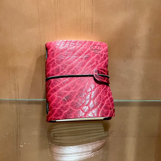 Pink leather wallet on a glass surface with a wooden background