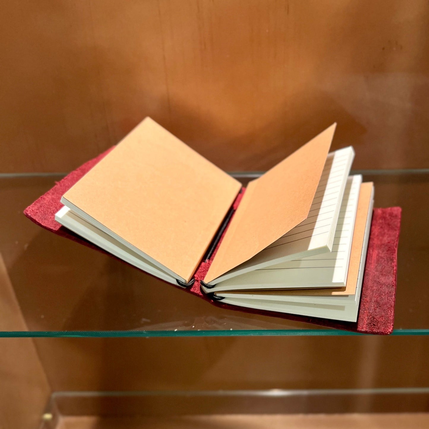 Open notebook on a glass shelf with a wooden background