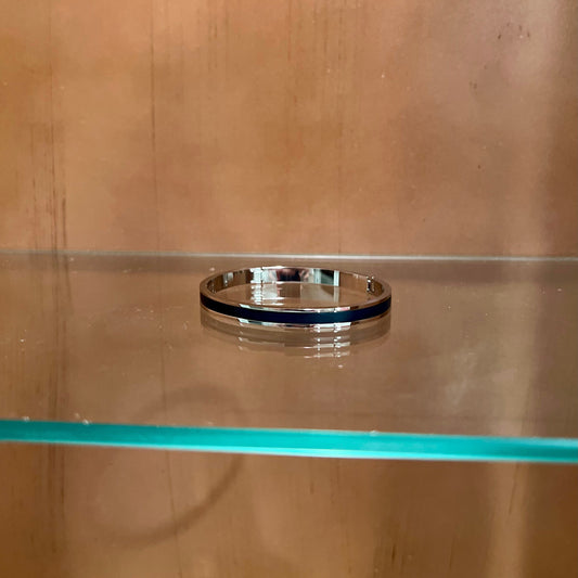 Silver ring on a glass shelf with a wooden wall background