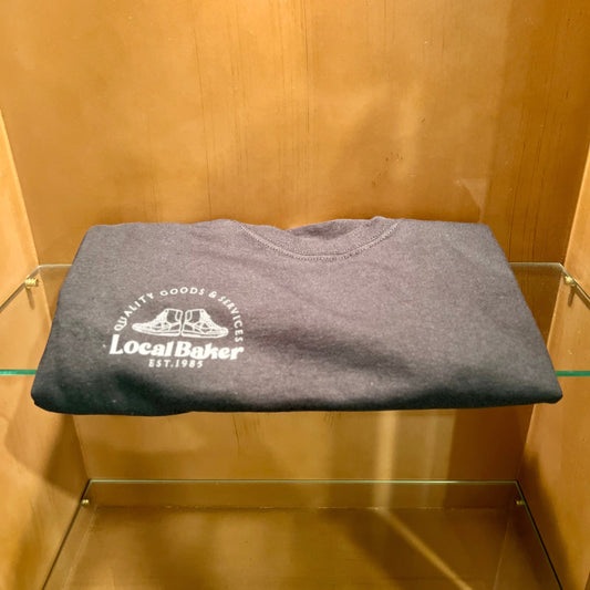 Folded gray t-shirt with a logo on a glass shelf against a wooden wall