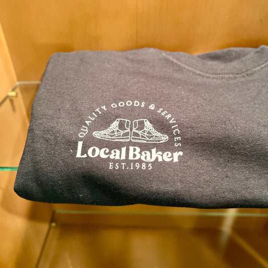 Folded gray t-shirt with 'Local Baker' logo on a wooden surface