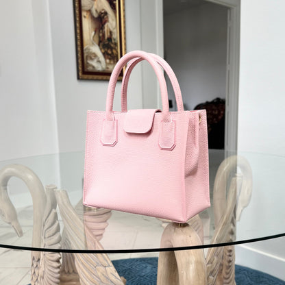 Pink handbag on a decorative stand with a painting in the background