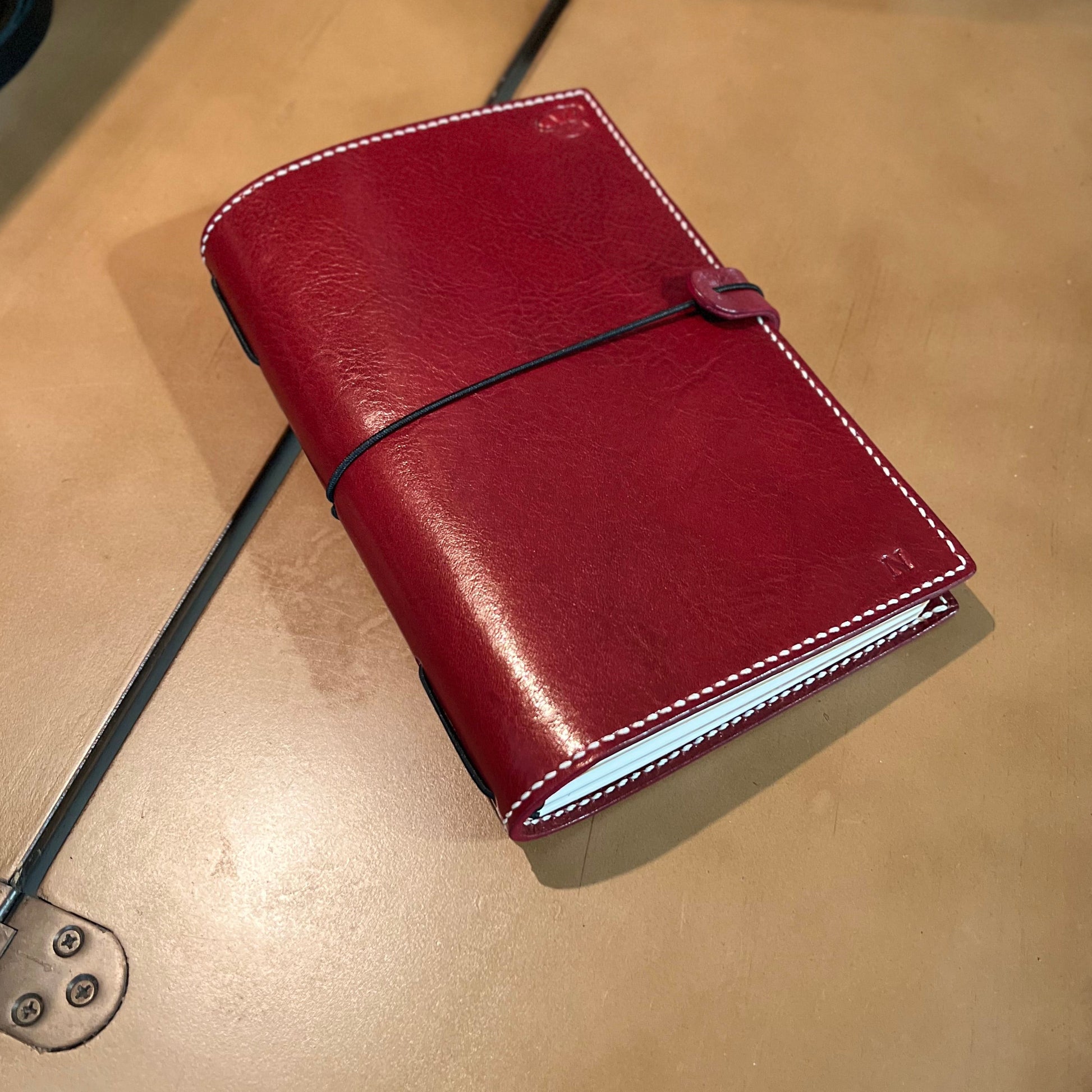 Red leather notebook on a beige suitcase